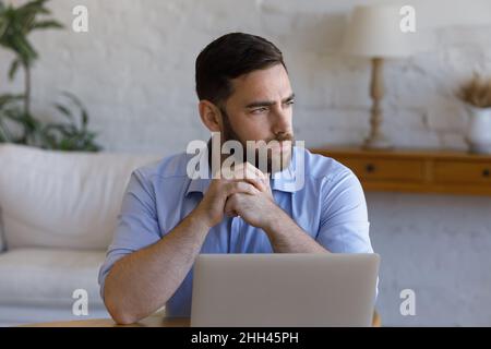 Homme d'affaires sérieux et attentionné travaillant à table avec un ordinateur portable Banque D'Images