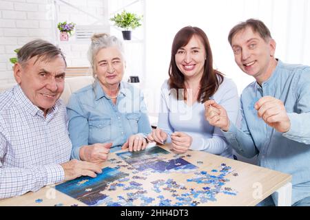 parents âgés heureux et couple d'âge moyen travaillant sur un puzzle ensemble à la maison Banque D'Images