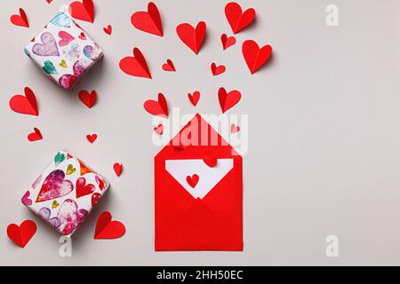 Enveloppe avec lettre d'amour pour la Saint-Valentin.Cadeaux et coeurs en papier sur fond gris. Banque D'Images