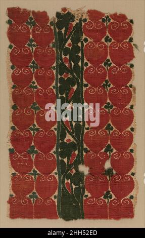 Fragment textile 4th–5th siècle les textiles anciens tardifs d'Égypte varient grandement dans leur conception, leur technique et leur qualité.Ce textile est particulièrement remarquable pour ses couleurs vives et son esthétique graphique.Deux rangées de formes rouges similaires à un cœur se répètent des deux côtés d'un scroll de vigne vert profond.Comme les textiles portés sur le corps avaient tendance à employer des conceptions plus complexes, il est possible que cette pièce faisait partie d'un mur suspendu.Fragment textile 443843 Banque D'Images