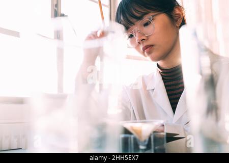 Jeune chimiste travaillant avec concentration en laboratoire Banque D'Images