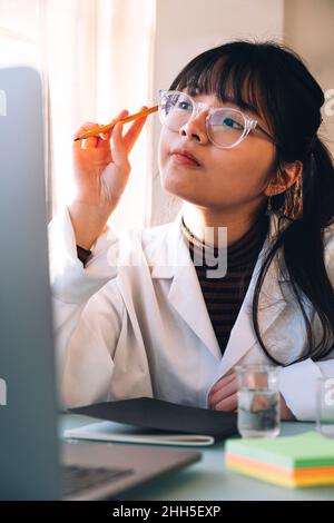 Jeune scientifique portant des lunettes de vue contemplant en laboratoire Banque D'Images