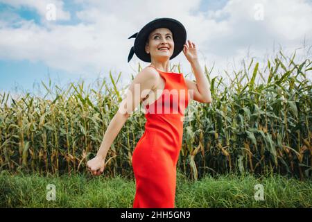 Belle femme souriante avec chapeau debout devant le champ de maïs Banque D'Images