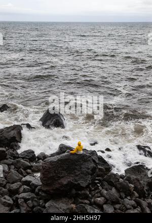 Jeune homme sur roche volcanique regardant la mer, Rocha Da Relva, île de San Miguel, Açores, Portugal Banque D'Images