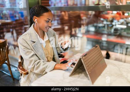 Fille faisant le paiement en ligne par carte de crédit sur l'écran tactile ordinateur portable au café Banque D'Images