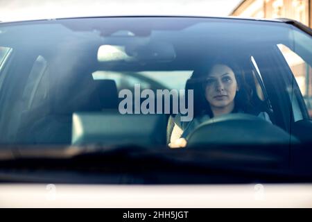 Femme conduisant une voiture électrique vue par le pare-brise Banque D'Images