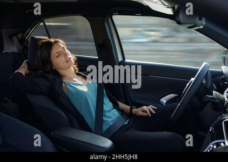 Femme d'affaires fatiguée dormant dans une voiture autonome sans conducteur Banque D'Images