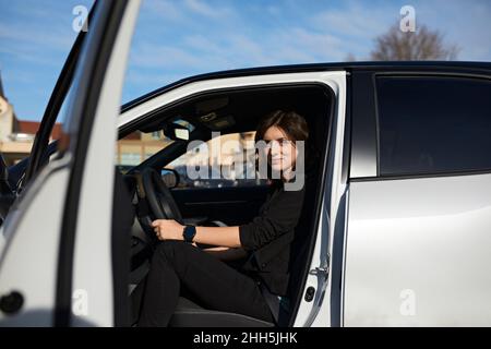 Femme d'affaires assise sur le siège du conducteur dans la voiture Banque D'Images