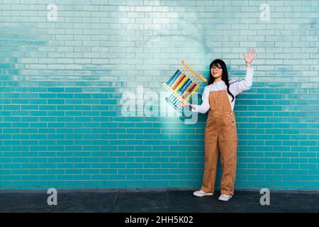 Femme équilibrant abacus sur la main devant le mur turquoise Banque D'Images