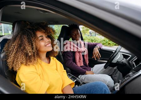 Homme souriant regardant un ami assis en voiture Banque D'Images