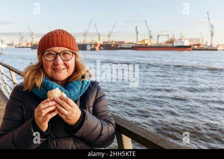 Femme âgée ayant un sandwich par la rivière Elbe Banque D'Images