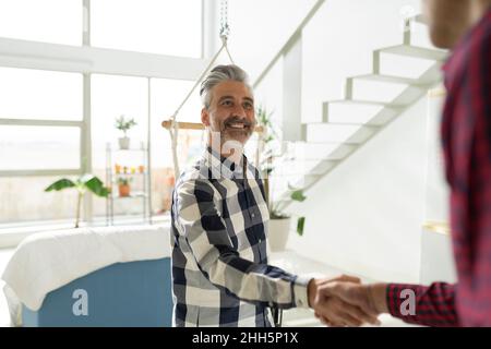 Agent immobilier qui se fait la main avec le client à la maison Banque D'Images