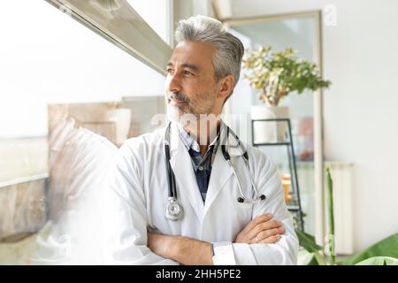 Médecin attentionné avec bras croisés, vue sur la fenêtre Banque D'Images