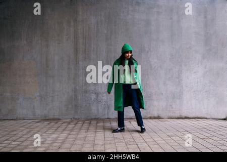 Jeune femme en manteau d'hiver vert debout sur la piste de marche Banque D'Images