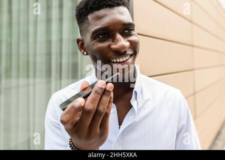 Joyeux homme qui envoie la boîte vocale sur un smartphone Banque D'Images