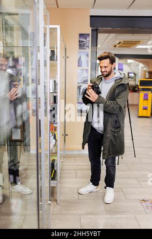 Homme souriant magasiner caméra dans le magasin Banque D'Images