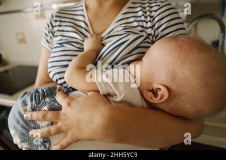 Mère transportant un enfant et allaitant à la maison Banque D'Images