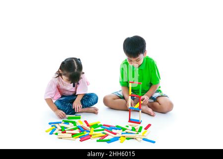 Les enfants asiatiques sont heureux. Garçon et fille jouant des blocs de bois de jouet, isolés sur fond blanc. Jouets éducatifs pour enfants de l'élémentaire et de la maternelle. Tre Banque D'Images