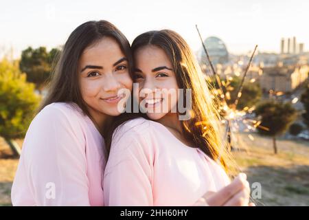 Jeune femme avec sœur souriante tenant des scintiers Banque D'Images