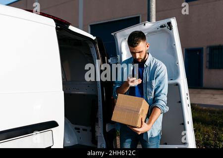Jeune homme lisant la boîte de livraison par camion Banque D'Images