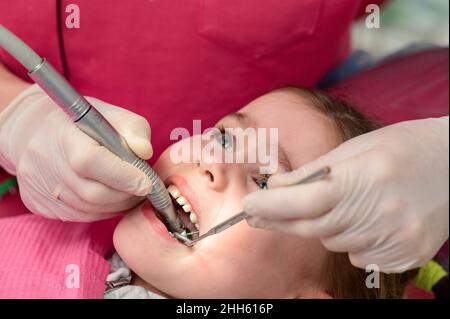 Le dentiste pédiatrique traite les dents de l'enfant, l'examen de la dent après le nettoyage des caries. Banque D'Images