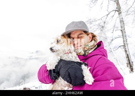 Homme embrassant le terrier Jack Russell pendant les vacances d'hiver Banque D'Images