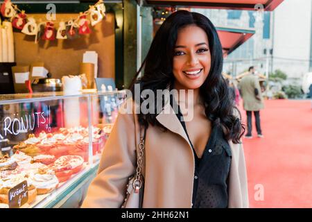 Une femme heureuse se tenant près d'un magasin de beignets sur le marché Banque D'Images