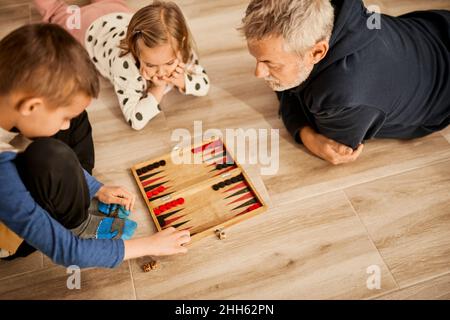 Grand-père jouant du backgammon avec des petits-enfants à la maison Banque D'Images