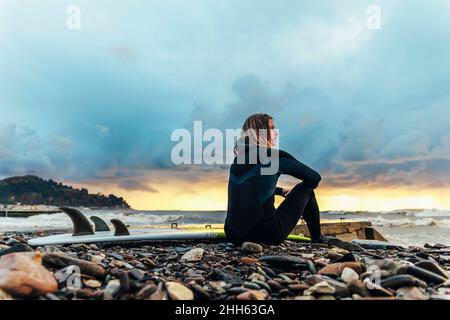 Surfeur attentionné assis à la planche de surf sur la plage Banque D'Images