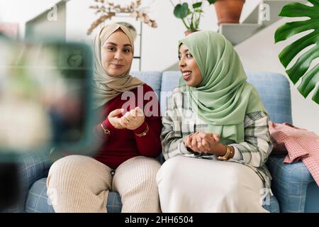 Des amis souriants aux mains classed assis sur le canapé dans le salon Banque D'Images