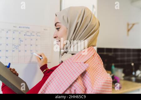 Jeune femme écrivant sur le papier à la maison Banque D'Images