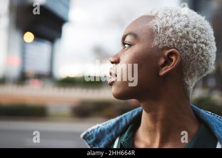 Jeune femme aux cheveux blonds courts regardant loin Banque D'Images