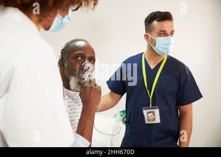 Patient ajustant le masque d'oxygène en regardant le médecin dans la salle médicale Banque D'Images