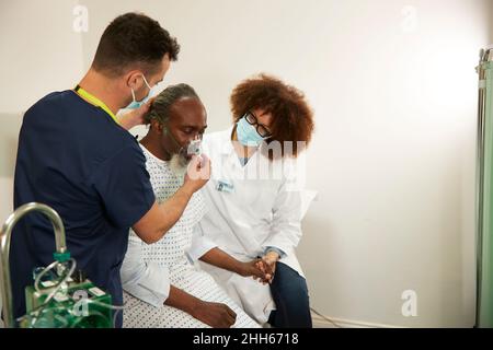 Infirmière ajustant le masque d'oxygène du patient avec un médecin dans la salle médicale Banque D'Images