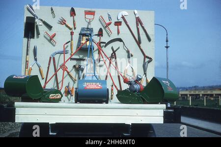 1959, historique, un défilé flottant présentant une gamme d'outils de jardin et plusieurs tondeuses à gazon de l'époque, y compris le Suffolk Viceroy tondeuse à essence, Londonderry, Irlande du Nord, Royaume-Uni. Banque D'Images