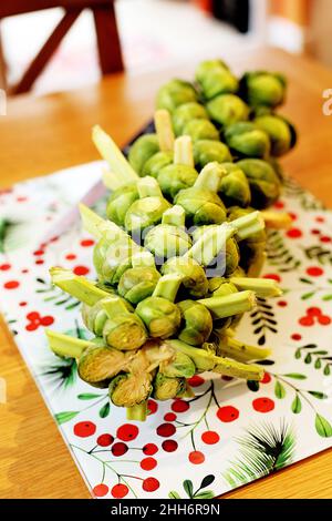 Une tige de choux de Bruxelles prête pour la préparation de la cuisine se trouve sur un plan de travail/table de cuisine à côté d'un couteau tranchant Banque D'Images