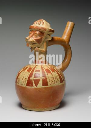 Fox Warrior Bottle 4th–6th Century Moche cette bouteille à bec d'étrier, conçue par des gens de la culture Moche sur la côte nord du Pérou, représente un renard anthropomorphique avec des attributs humains représentés en trois dimensions.Le dessus tridimensionnel de la bouteille peut être interprété soit comme un club de guerre zoomorphisé, soit comme un guerrier de renard nouant un headaddress en forme de mace sous son menton.Un spray de fruits ou de tubercules, peut-être des poivrons, est modelé sur le sommet du club.Les clubs, les lances et les cordes de casque peintes en rouge glissent du cou du navire à la circonférence de la chambre.Dans deux et thr Banque D'Images