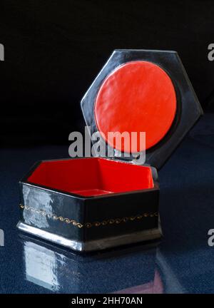 Une boîte laquée noire avec un intérieur rouge.Objets sur fond noir Banque D'Images