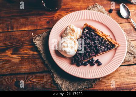 Tranche de tarte aux fruits rouges maison et deux Scoops de glace à la vanille sur une assiette sur une table en bois Banque D'Images