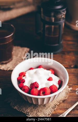 Dessert sain avec framboise fraîche et crème sure dans un bol et un verre de café Banque D'Images