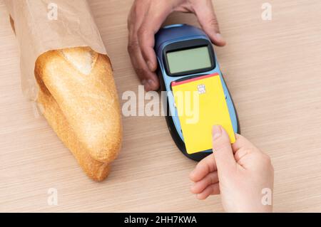 Gros plan d'un client effectuant un paiement par carte de crédit dans une boulangerie Banque D'Images