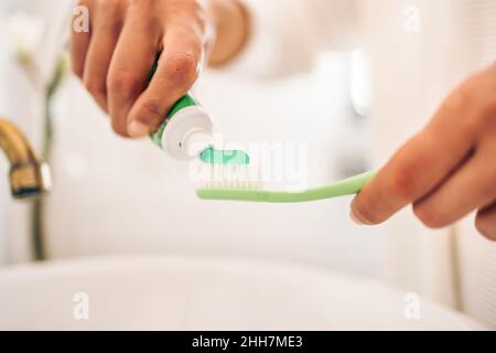 Gros plan sur une femme qui met du dentifrice sur une brosse à dents Banque D'Images