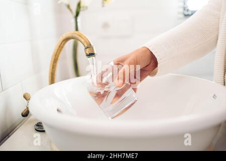 remplir un verre d'eau dans le lavabo de la salle de bains Banque D'Images