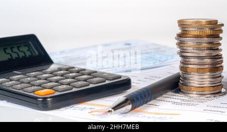 Colcolonne de pièces sur fond de factures et de chèques, calculatrice et stylo.Concept financier et bancaire, finances à domicile Banque D'Images