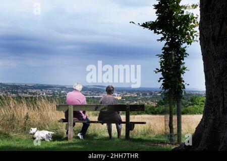 Une femme et une femme assise sur un banc sur Highdown Hill, Worthing, Royaume-Uni, profitant de la vue sur la mer Banque D'Images