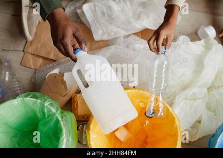 Vue de dessus gros plan de père et fils afro-américains mettant du plastique dans des bacs de recyclage à la maison, espace de copie Banque D'Images