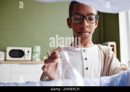 Gros plan sur le tri des déchets ménagers chez un garçon et la mise d'une bouteille en plastique dans un bac de recyclage, dans l'espace de copie Banque D'Images