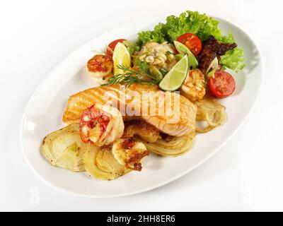 Filet de poisson poêlé au carb sur les légumes grillés - saumon rôti et crevettes sur une assiette isolée sur fond blanc Banque D'Images