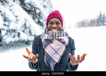 homme brésilien posant à l'extérieur dans une forêt d'hiver avec un bacille de neige Banque D'Images