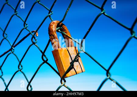 Le ciel bleu donne un fond à un cadenas rouillé sur une vieille clôture Banque D'Images